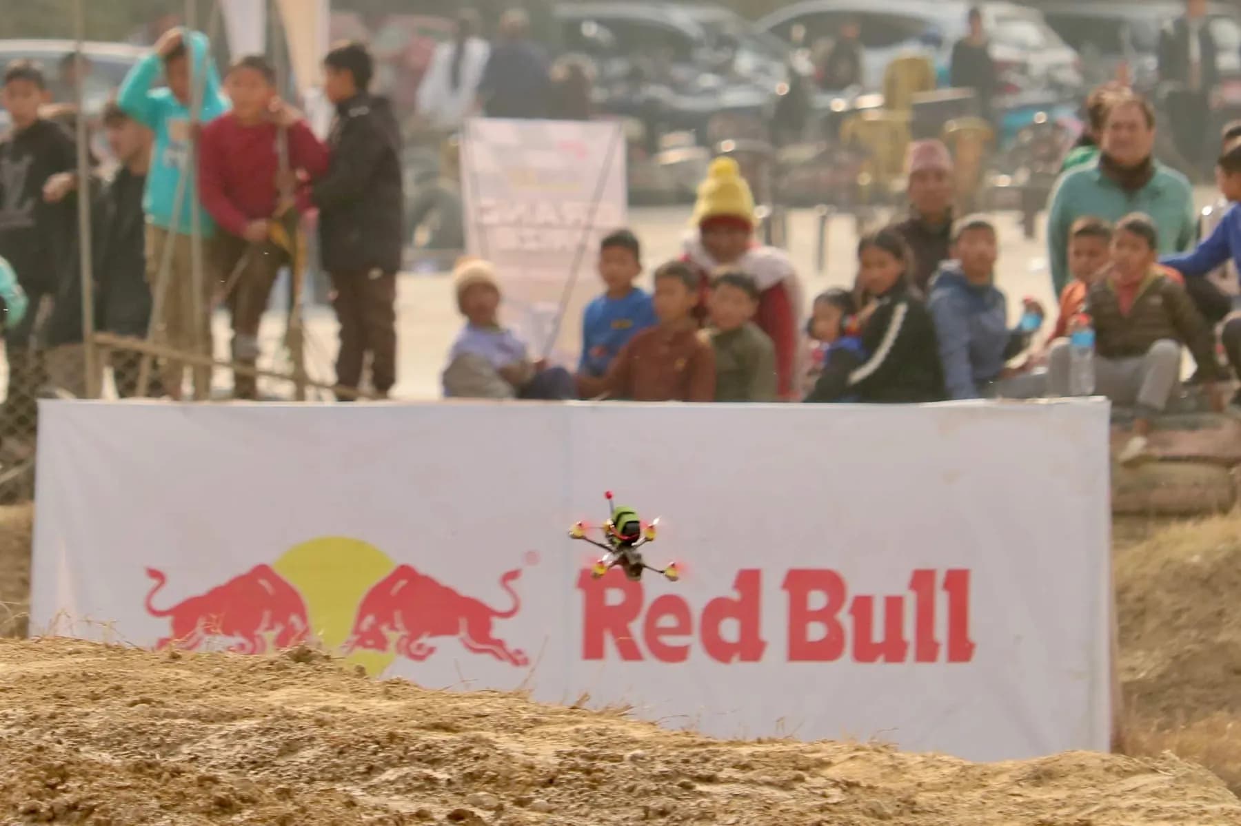An FPV racing drone passing a Red Bull banner at a drone race in Nepal