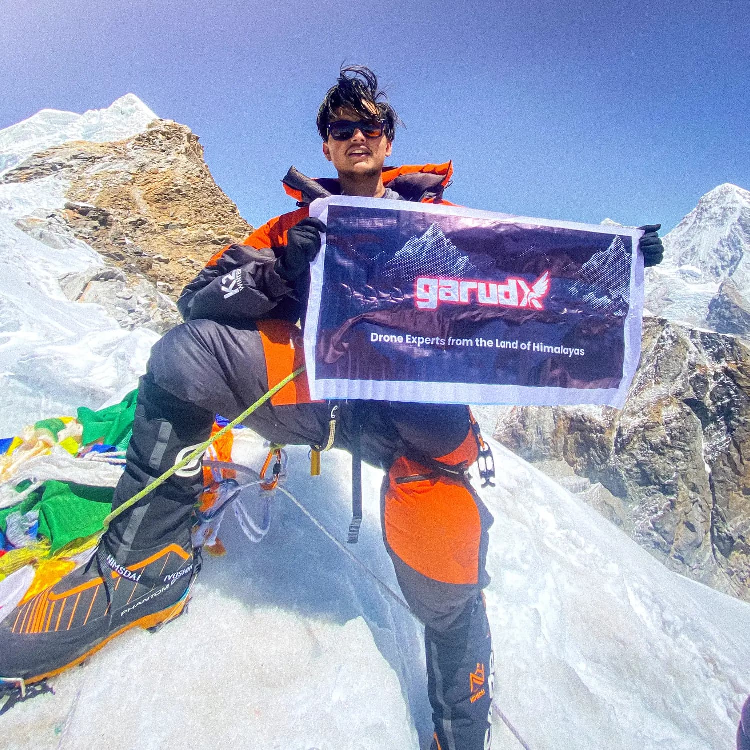 Adarsha near the summit of Lobuche East holding the GarudX flag