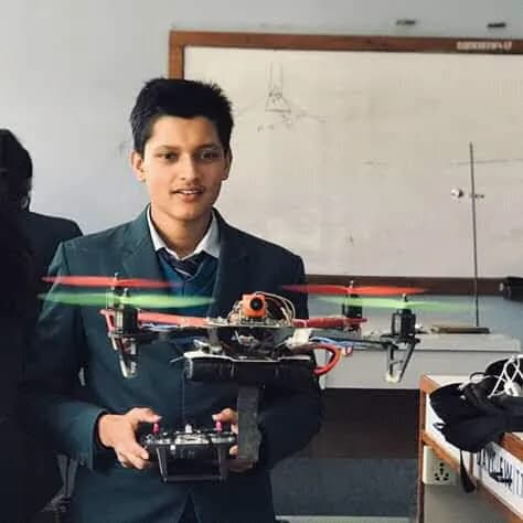 Adarsha in school uniform holding a quadcopter and its radio